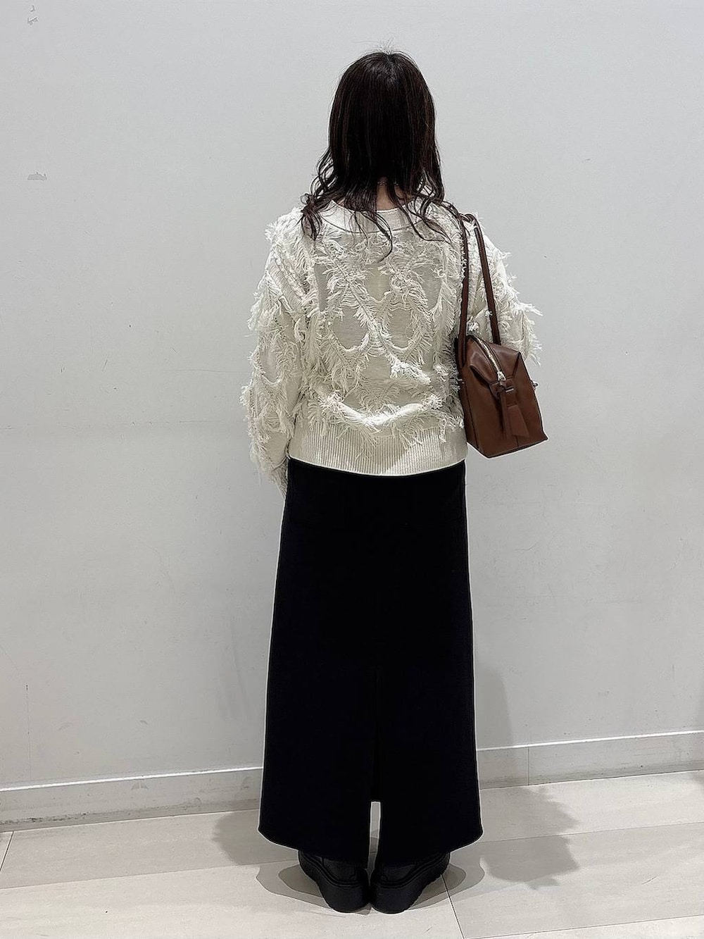 ブラウン系のボストンバッグ、ブラック系のブーツ、ホワイト系のカーディガン/ボレロを着用したレディースの冬コーディネートの3枚目の写真