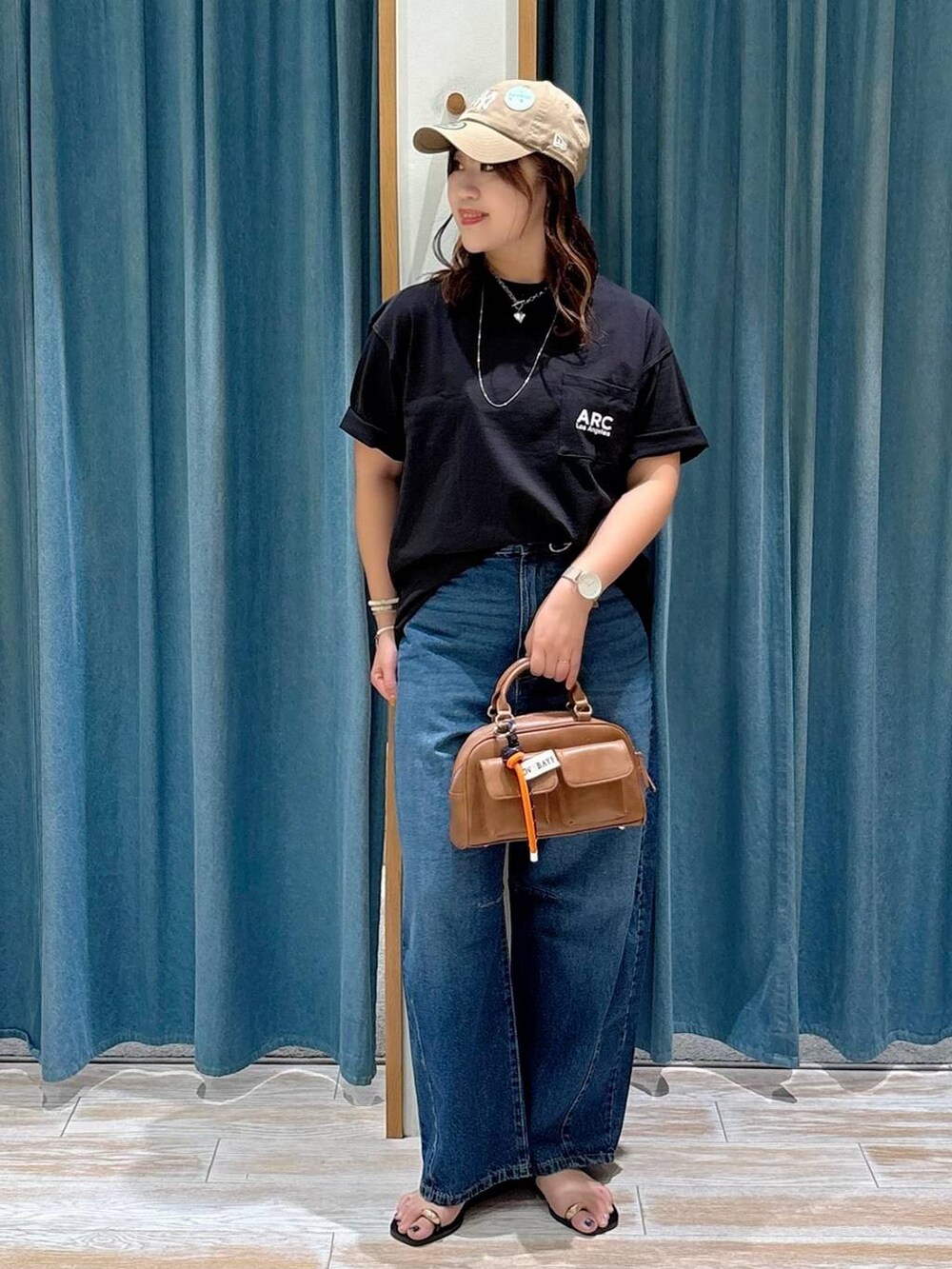 ブルー系のデニムパンツ、ブラック系のTシャツ/カットソー、ブラック系のサンダルを着用したレディースの夏コーディネートの2枚目の写真