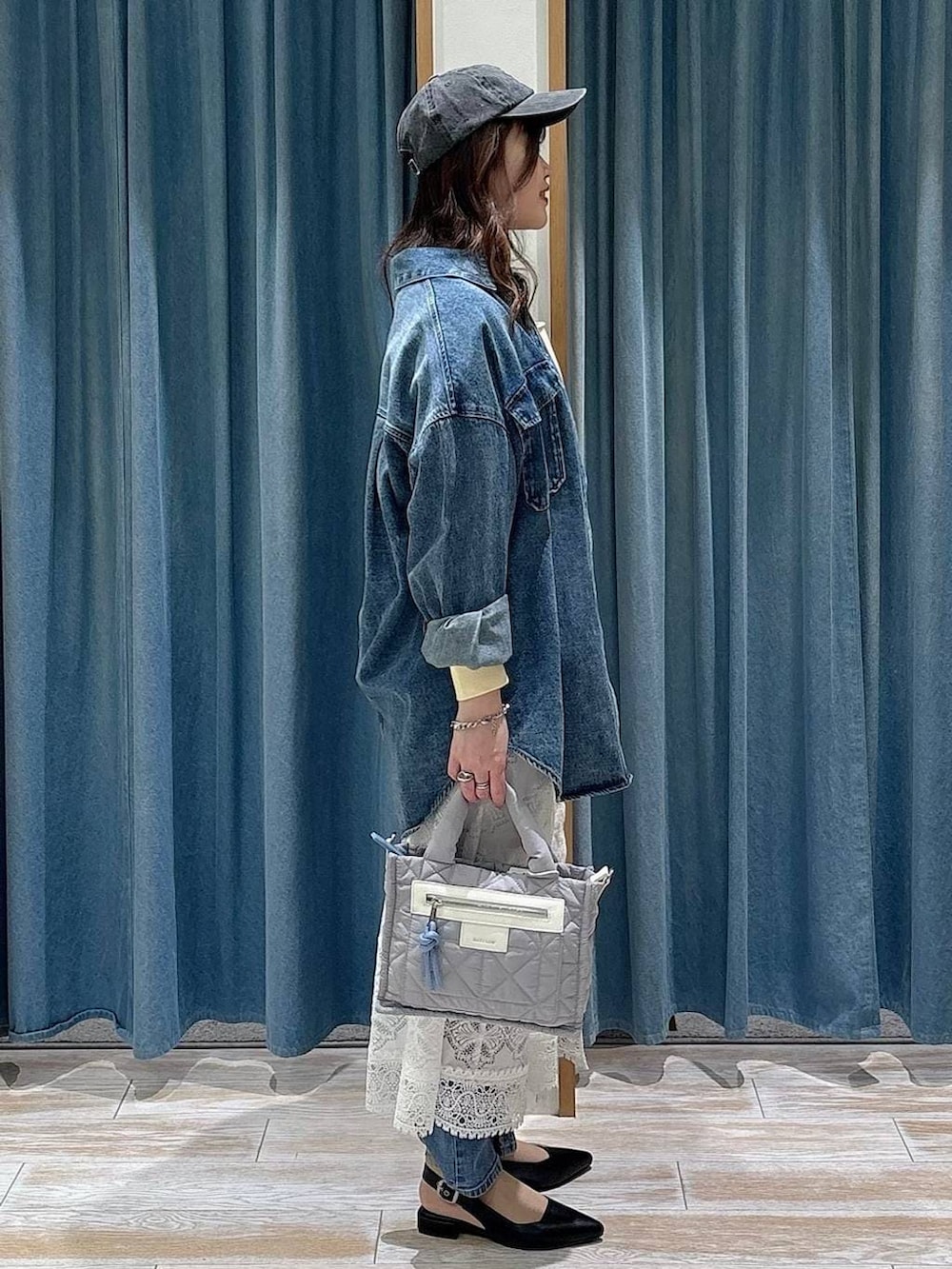 グレー系のショルダーバッグ、ブラック系のパンプス、ブルー系のデニムパンツを着用したレディースの冬コーディネートの2枚目の写真