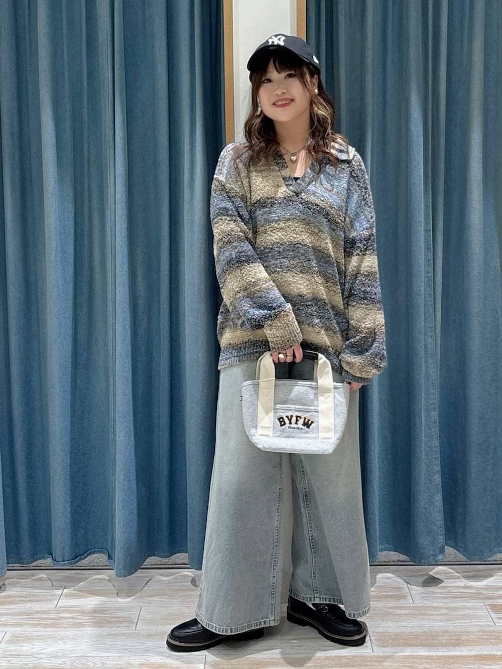 ブラック系のローファー、グレー系のトートバッグ、ブルー系のデニムパンツを着用したレディースの冬コーディネートの4枚目の写真