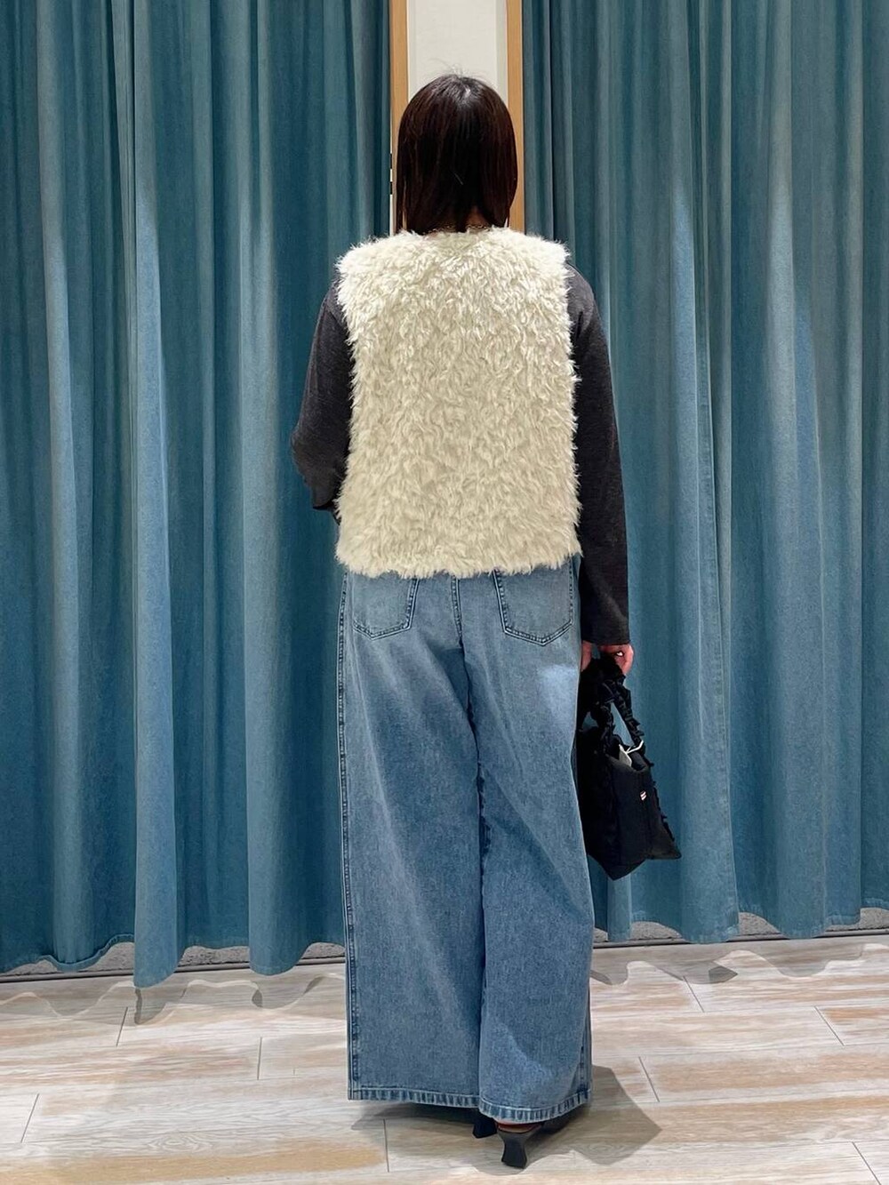 ブラック系のトートバッグ、ブルー系のデニムパンツ、ブラック系のパンプスを着用したレディースの冬コーディネートの2枚目の写真