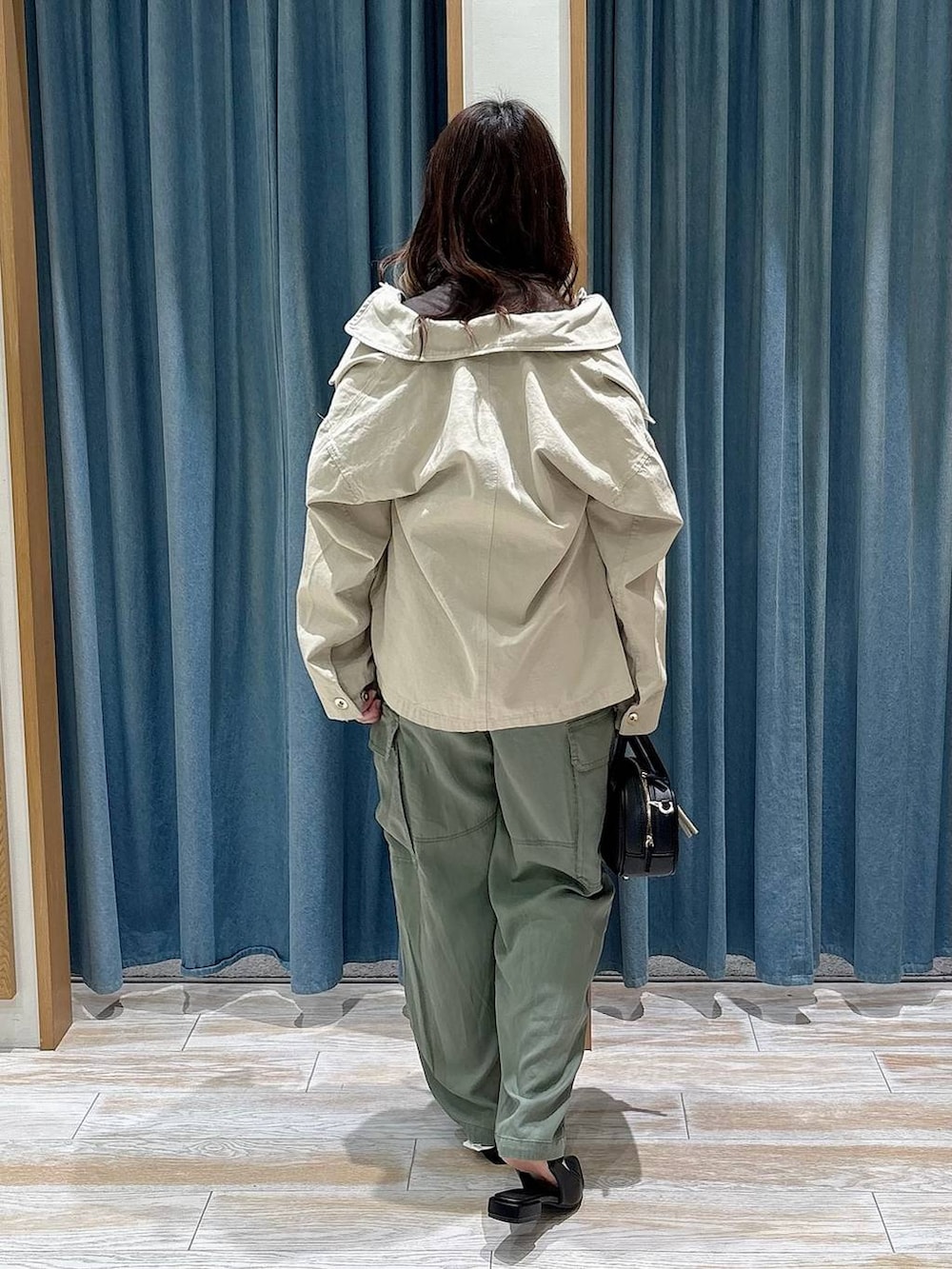 ブラック系のパンプス、ブラック系のハンドバッグ、ベージュ系のブルゾンを着用したレディースの春コーディネートの3枚目の写真