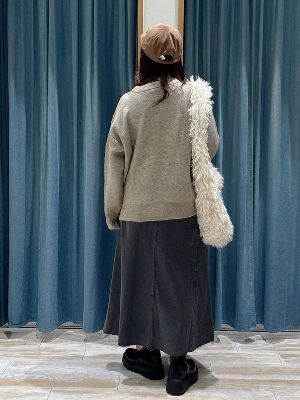 ブラック系のブーツ、ベージュ系のショルダーバッグ、ブラック系のスカートを着用したレディースの秋コーディネートの3枚目の写真