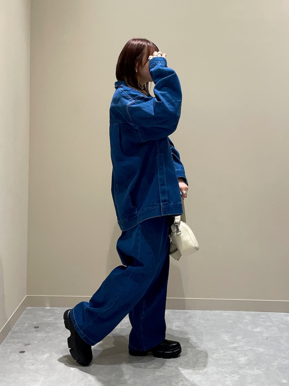 ブルー系のデニムジャケット、ブルー系のデニムパンツ、ホワイト系のショルダーバッグを着用したレディースの冬コーディネートの2枚目の写真