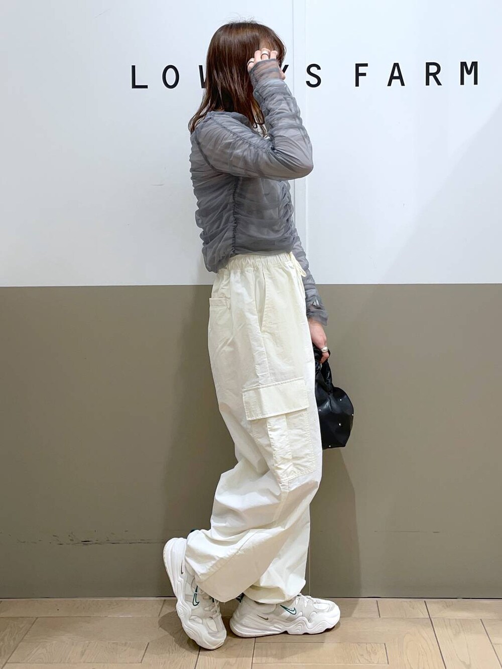 グレー系のシャツ/ブラウス、ブラック系のハンドバッグ、ホワイト系のカーゴパンツを着用したレディースの春コーディネートの2枚目の写真