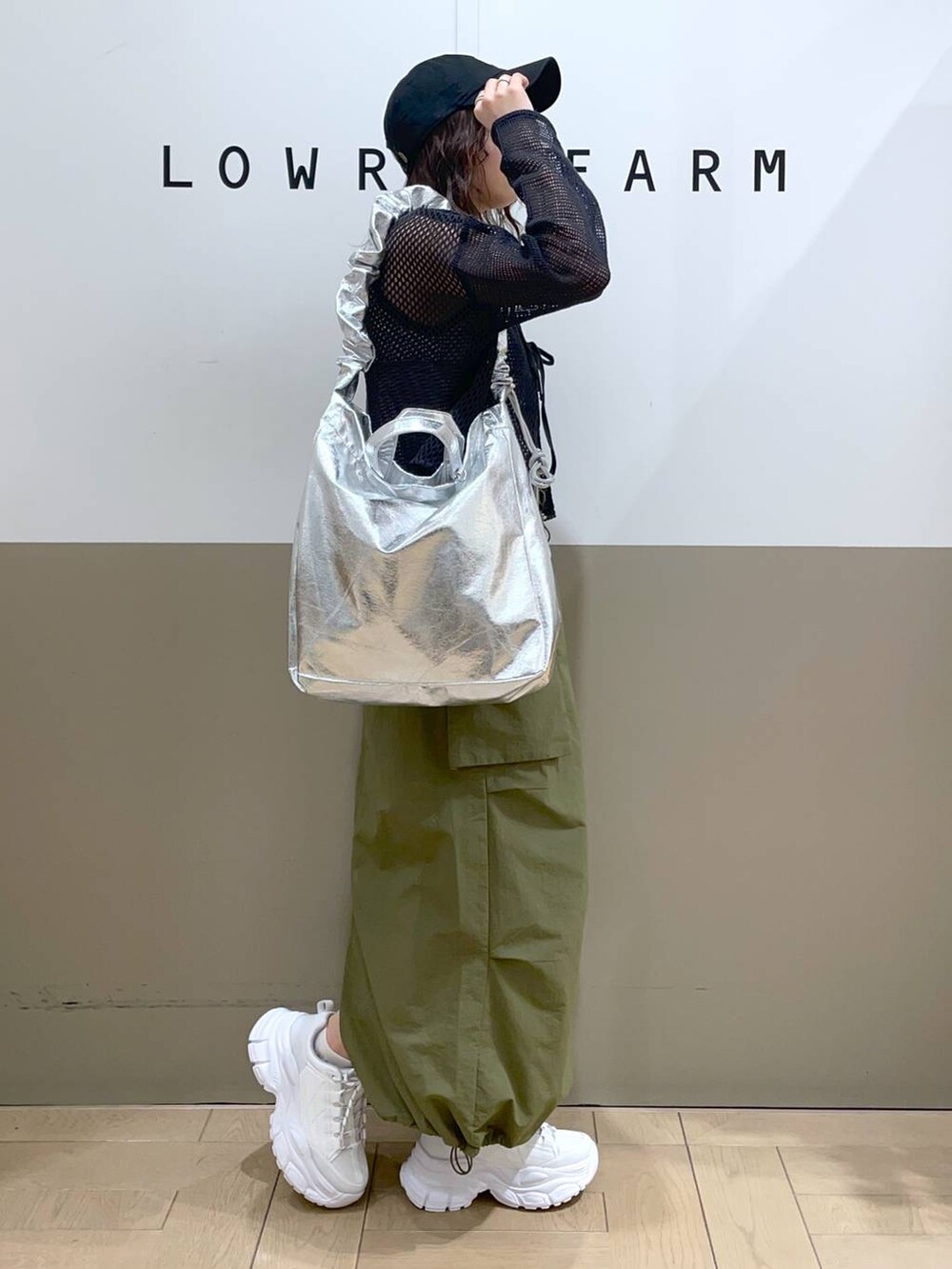 グレー系のトートバッグ、グレー系のニット/セーター、ブラック系のタンクトップを着用したレディースの春コーディネートの2枚目の写真