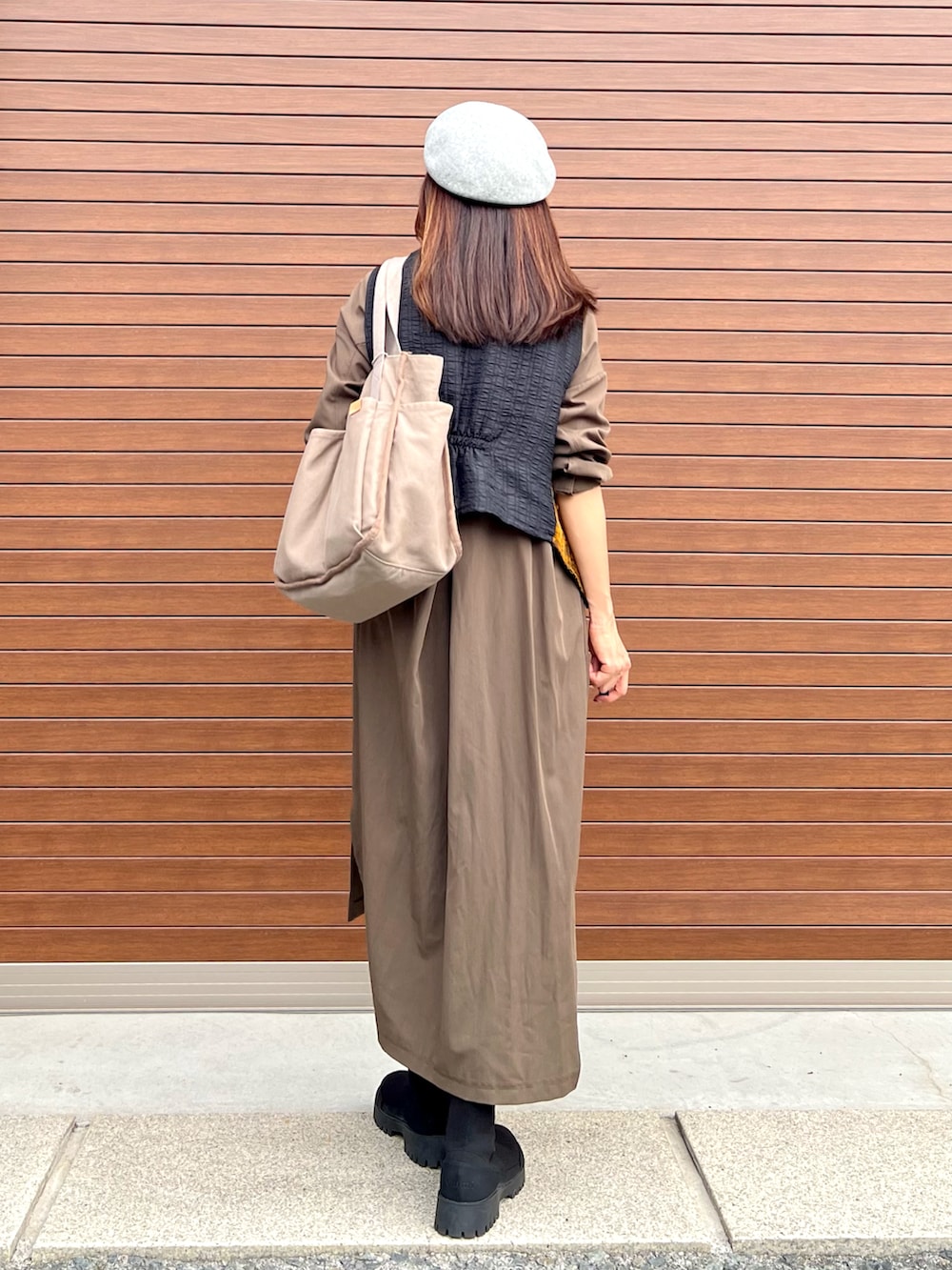 ベージュ系のトートバッグ、ブラック系のブーツ、ブラウン系のベストを着用したレディースの冬コーディネートの3枚目の写真