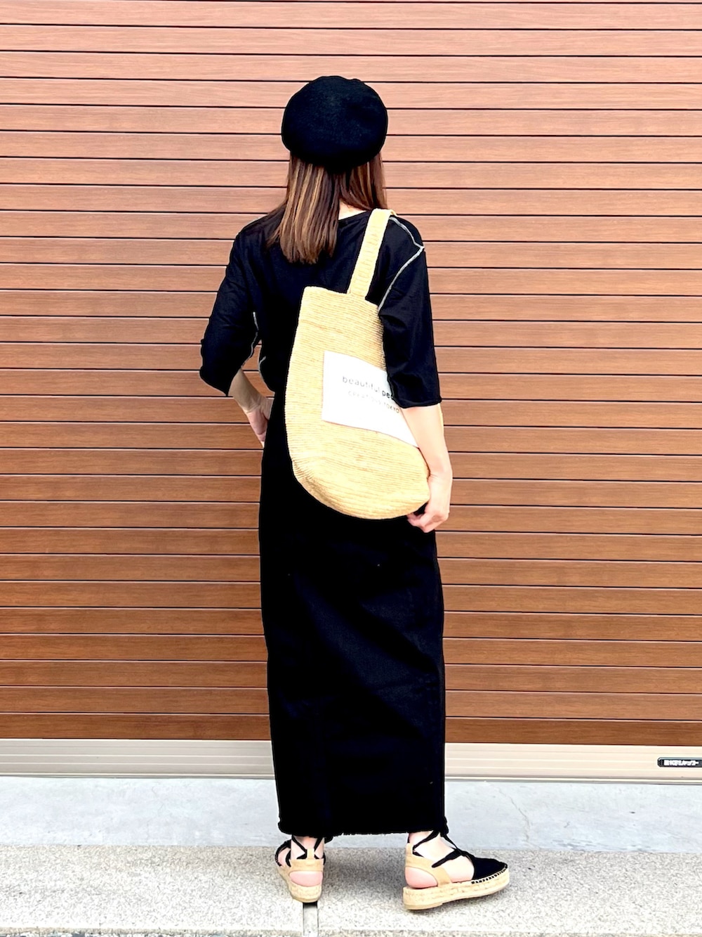 ベージュ系のトートバッグ、ブラック系のサンダル、ブラック系のTシャツ/カットソーを着用したレディースの夏コーディネートの3枚目の写真