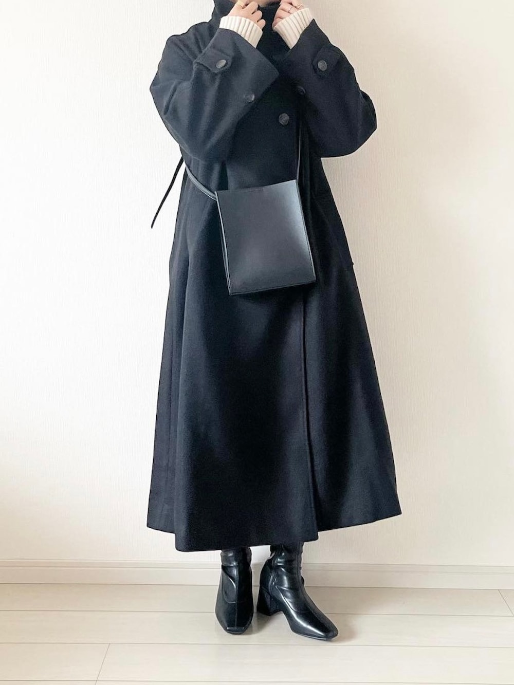 ホワイト系のニット/セーター、ブラック系のその他アウター、ブラック系のブーツを着用したレディースの秋コーディネートの2枚目の写真