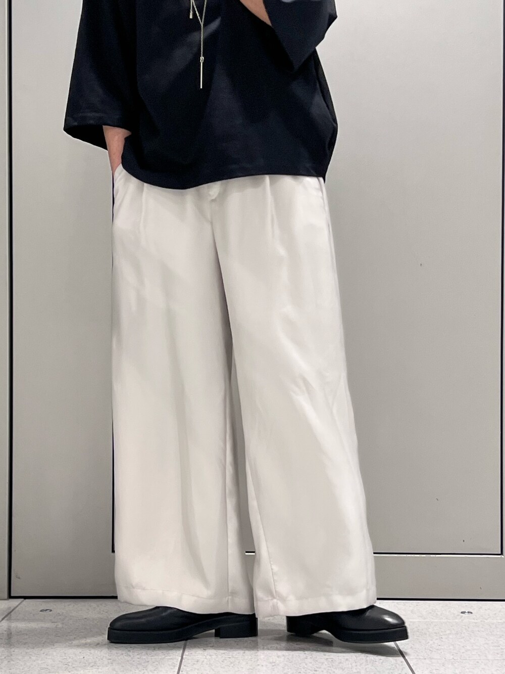 ブラック系のTシャツ/カットソー、シルバー系のトートバッグ、グレー系のスラックスを着用したメンズの春コーディネートの4枚目の写真