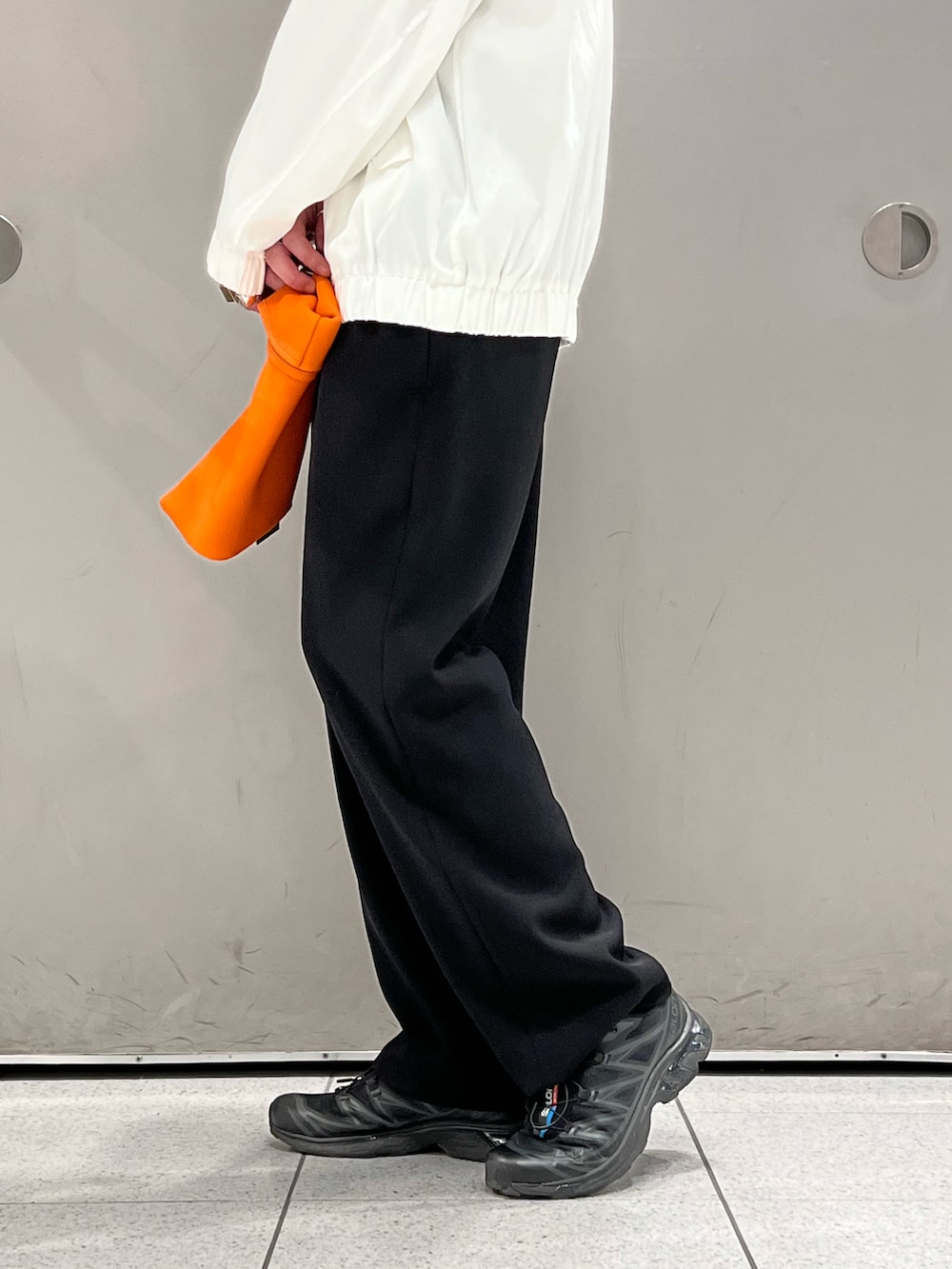 ホワイト系のブルゾン、オレンジ系のバッグ、ブラック系のその他パンツを着用したメンズの春コーディネートの3枚目の写真