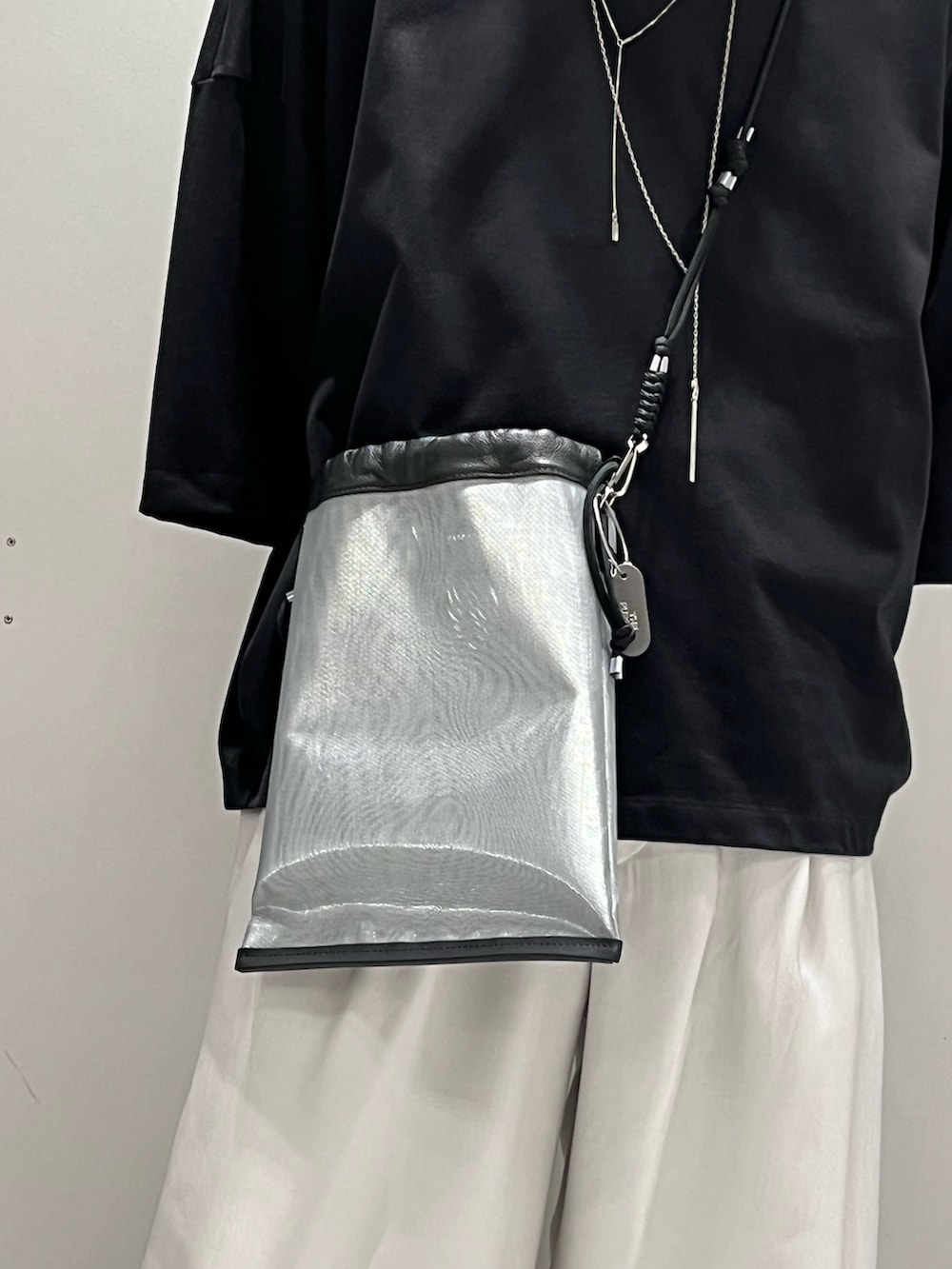 ブラック系のTシャツ/カットソー、シルバー系のトートバッグ、グレー系のスラックスを着用したメンズの春コーディネートの2枚目の写真