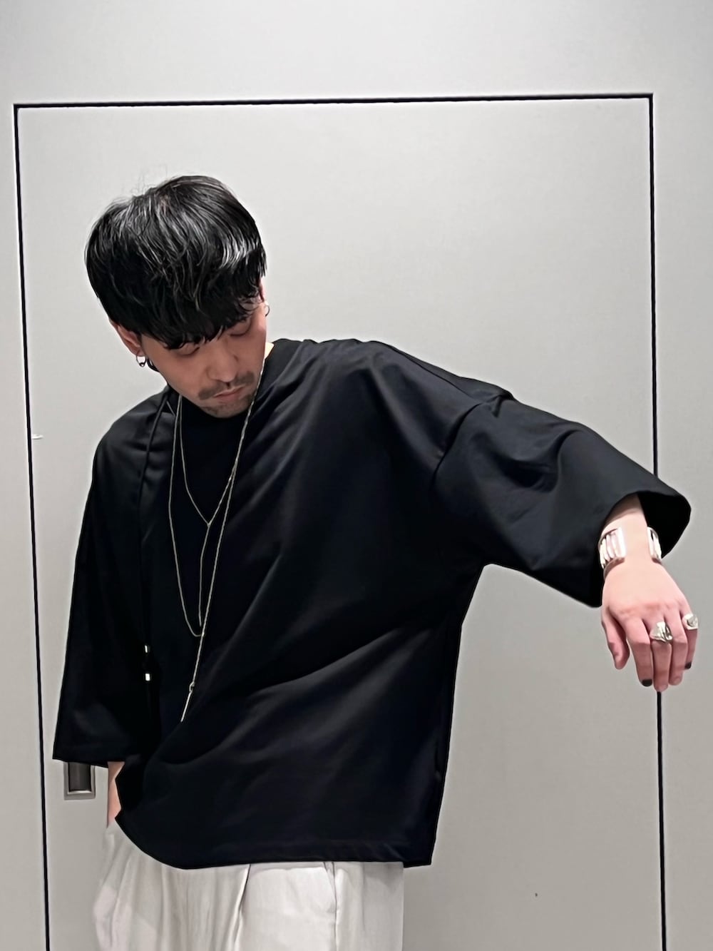 ブラック系のTシャツ/カットソー、シルバー系のトートバッグ、グレー系のスラックスを着用したメンズの春コーディネートの3枚目の写真