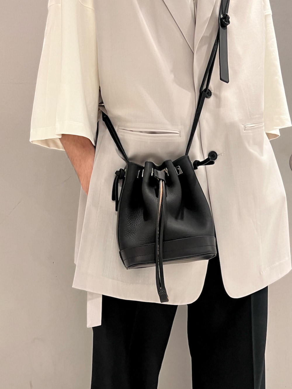 グレー系のベスト、ホワイト系のTシャツ/カットソー、ブラック系のトートバッグを着用したメンズの春コーディネートの3枚目の写真