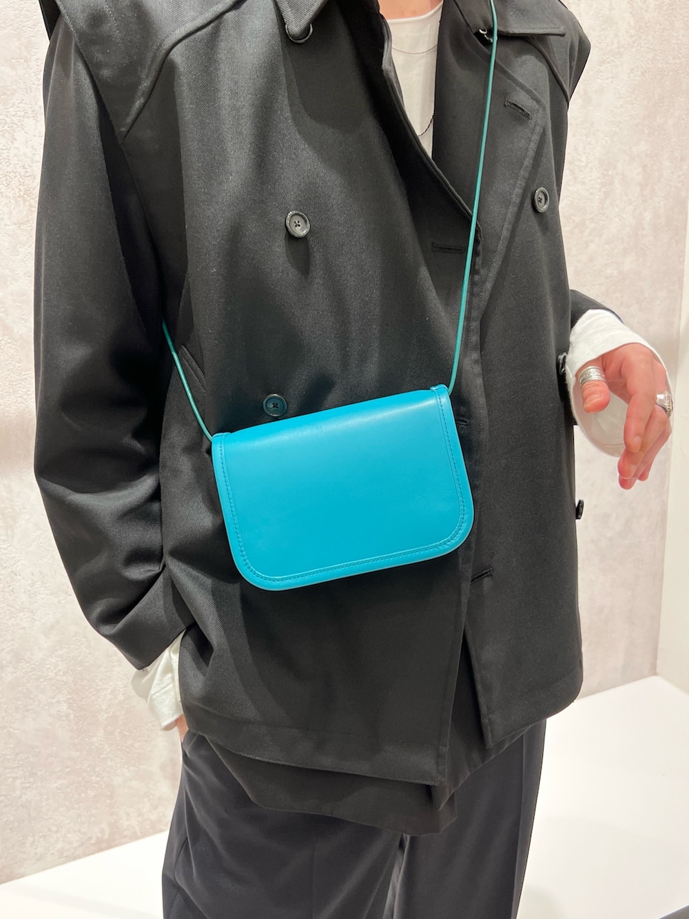 ブラック系のベスト、ブルー系のショルダーバッグ、ブラック系のテーラードジャケットを着用したメンズの秋コーディネートの4枚目の写真