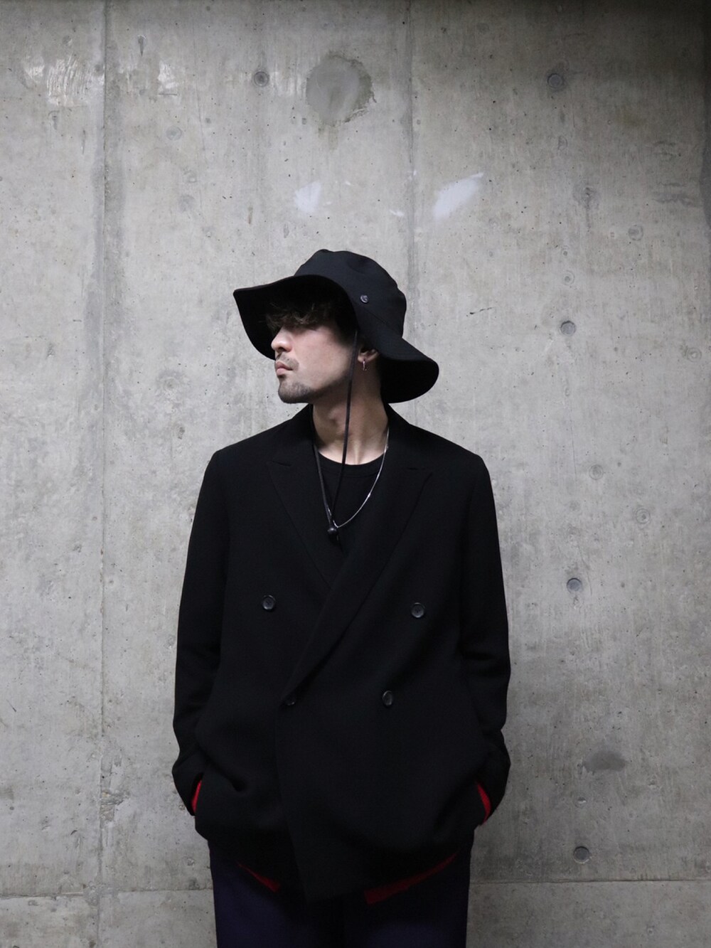 ブラック系のテーラードジャケット、レッド系のカーディガン/ボレロ、パープル系のパンツを着用したメンズの冬コーディネートの4枚目の写真