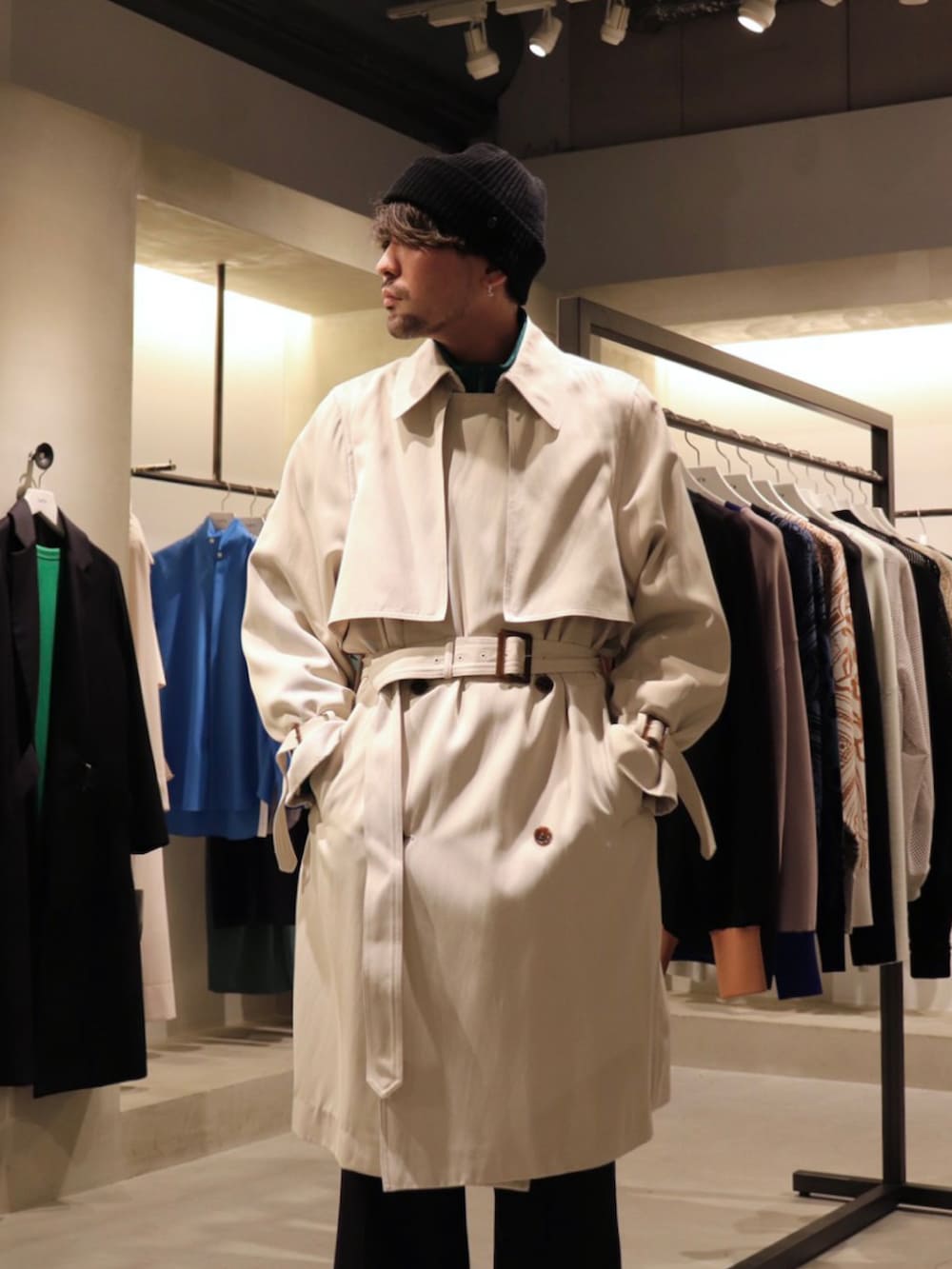 ベージュ系のトレンチコート、ブラック系のスラックス、グリーン系のブルゾンを着用したメンズの冬コーディネートの2枚目の写真