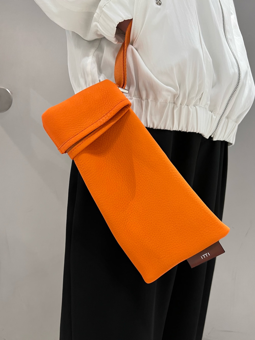 ホワイト系のブルゾン、オレンジ系のバッグ、ブラック系のその他パンツを着用したメンズの春コーディネートの5枚目の写真