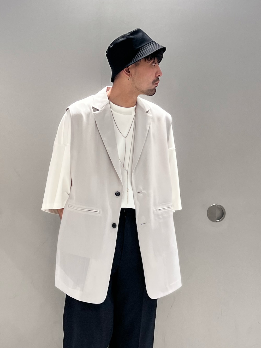 グレー系のベスト、ホワイト系のTシャツ/カットソー、ブラック系のトートバッグを着用したメンズの春コーディネートの4枚目の写真