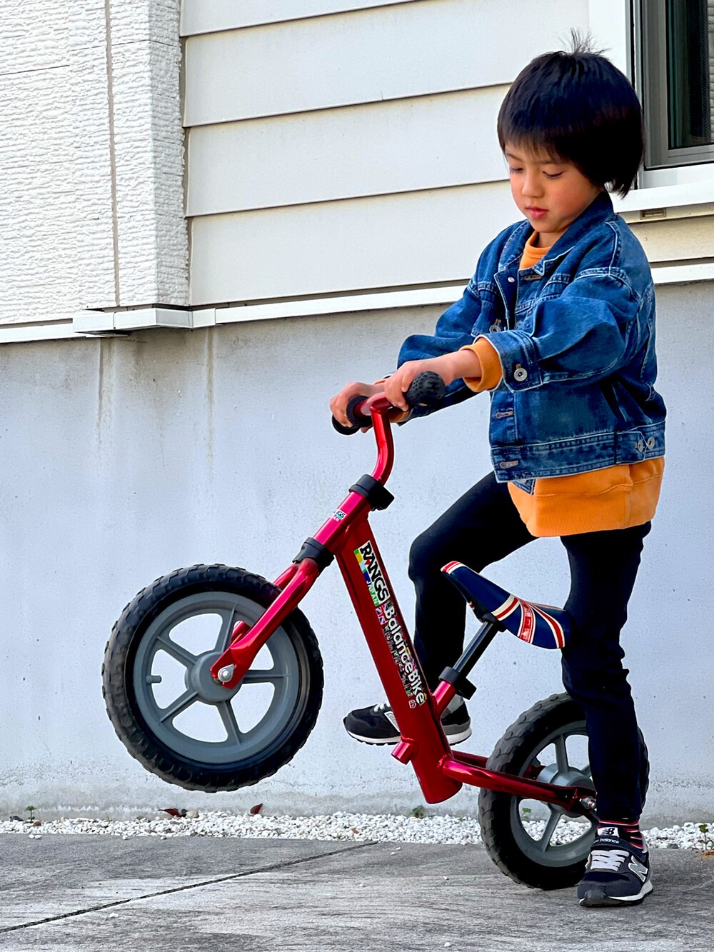 ブルー系のデニムジャケット、オレンジ系のスウェット、ブラック系のパンツを着用したキッズの春コーディネートの2枚目の写真