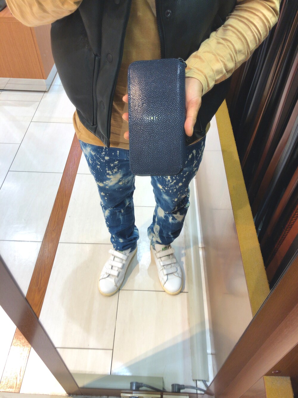 ブルー系のデニムパンツ、グリーン系のスニーカー、ブラック系のマウンテンパーカーを着用したメンズの冬コーディネートの3枚目の写真