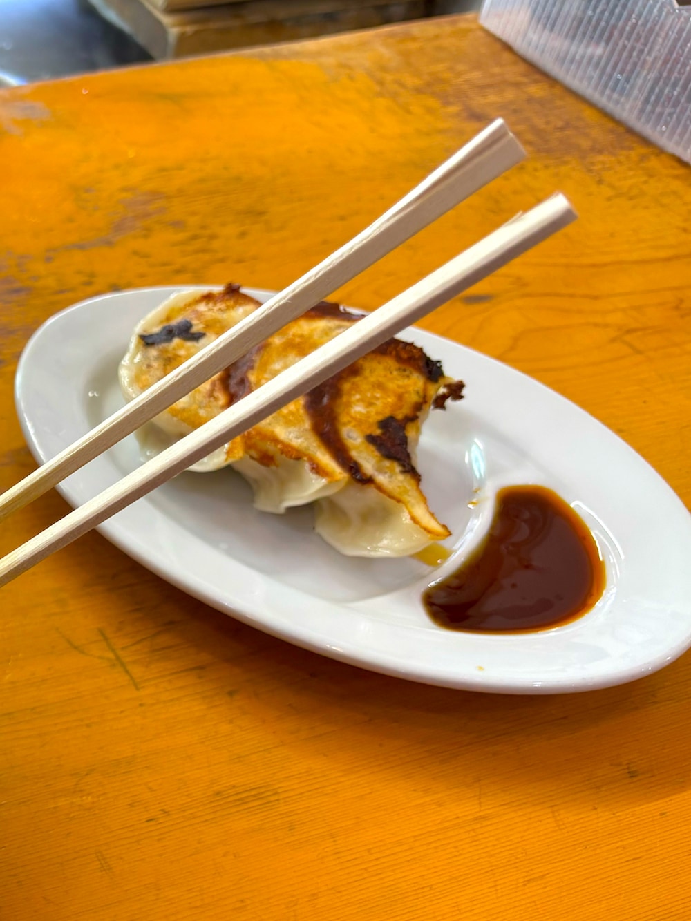 レッド系のシャツ/ブラウス、ブルー系のチェスターコート、グリーン系のチノパンツを着用したメンズの春コーディネートの3枚目の写真