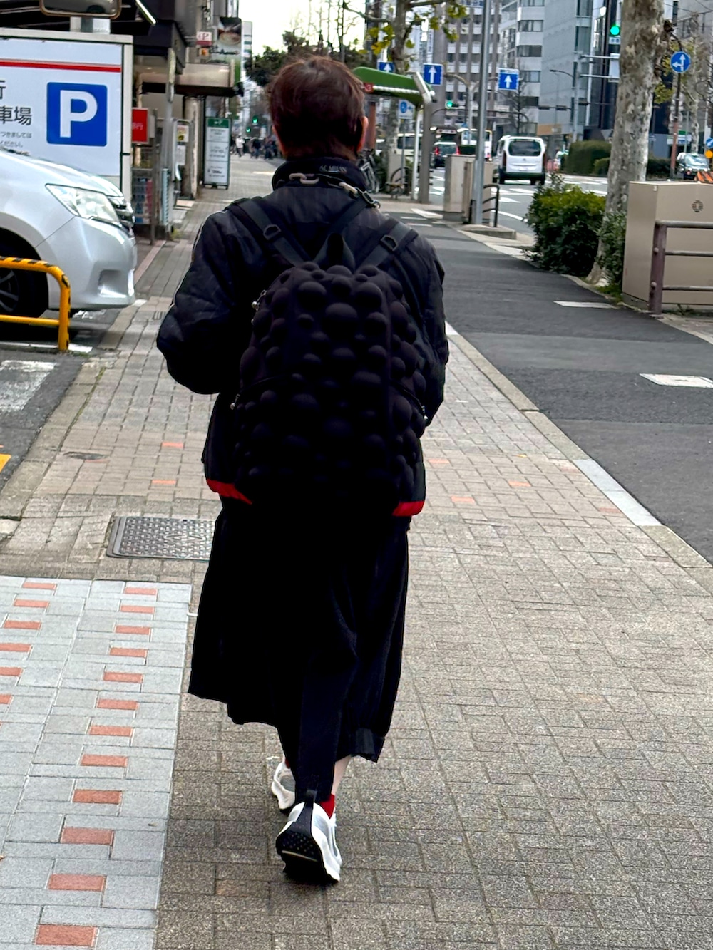 ブラック系のニット/セーター、ベージュ系のチェスターコート、ブルー系のデニムパンツを着用したメンズの冬コーディネートの4枚目の写真