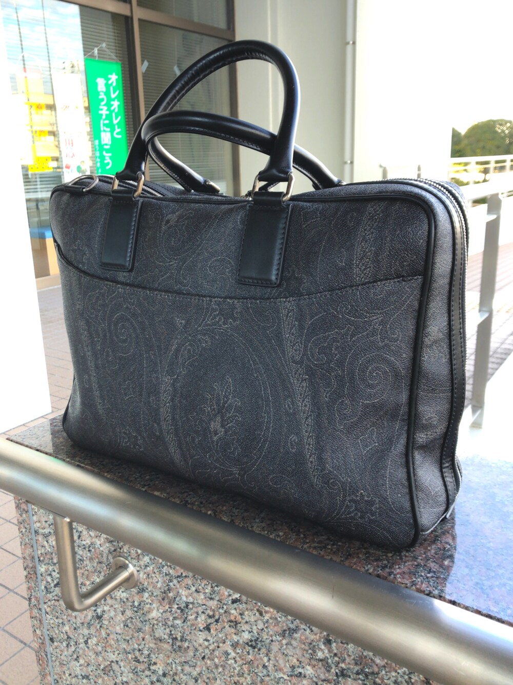 ブラウン系のブーツ、ブラック系のビジネスバッグ、ブルー系のチェスターコートを着用したメンズの冬コーディネートの2枚目の写真