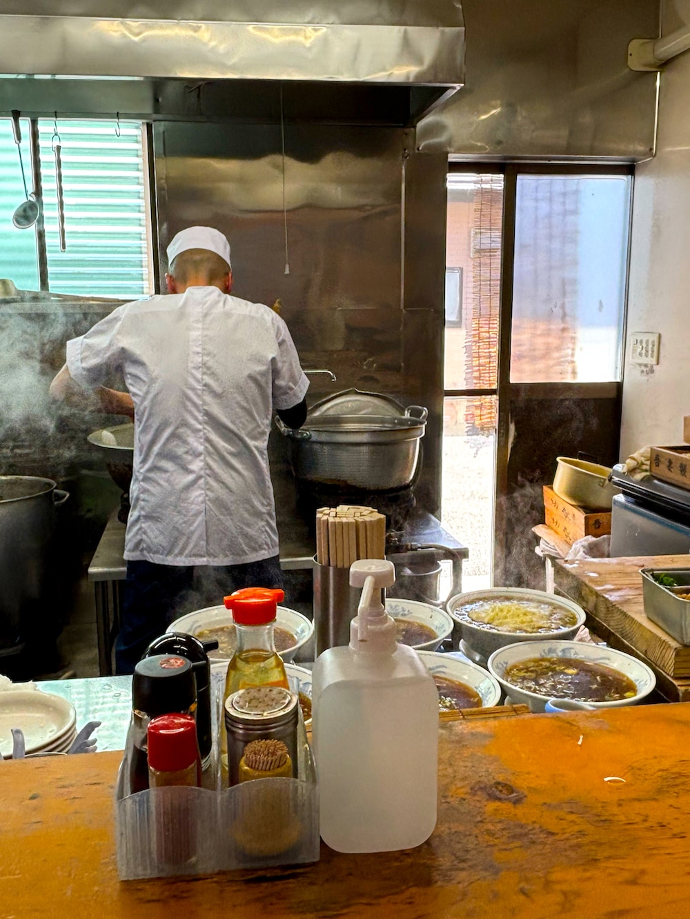 レッド系のシャツ/ブラウス、ブルー系のチェスターコート、グリーン系のチノパンツを着用したメンズの春コーディネートの4枚目の写真