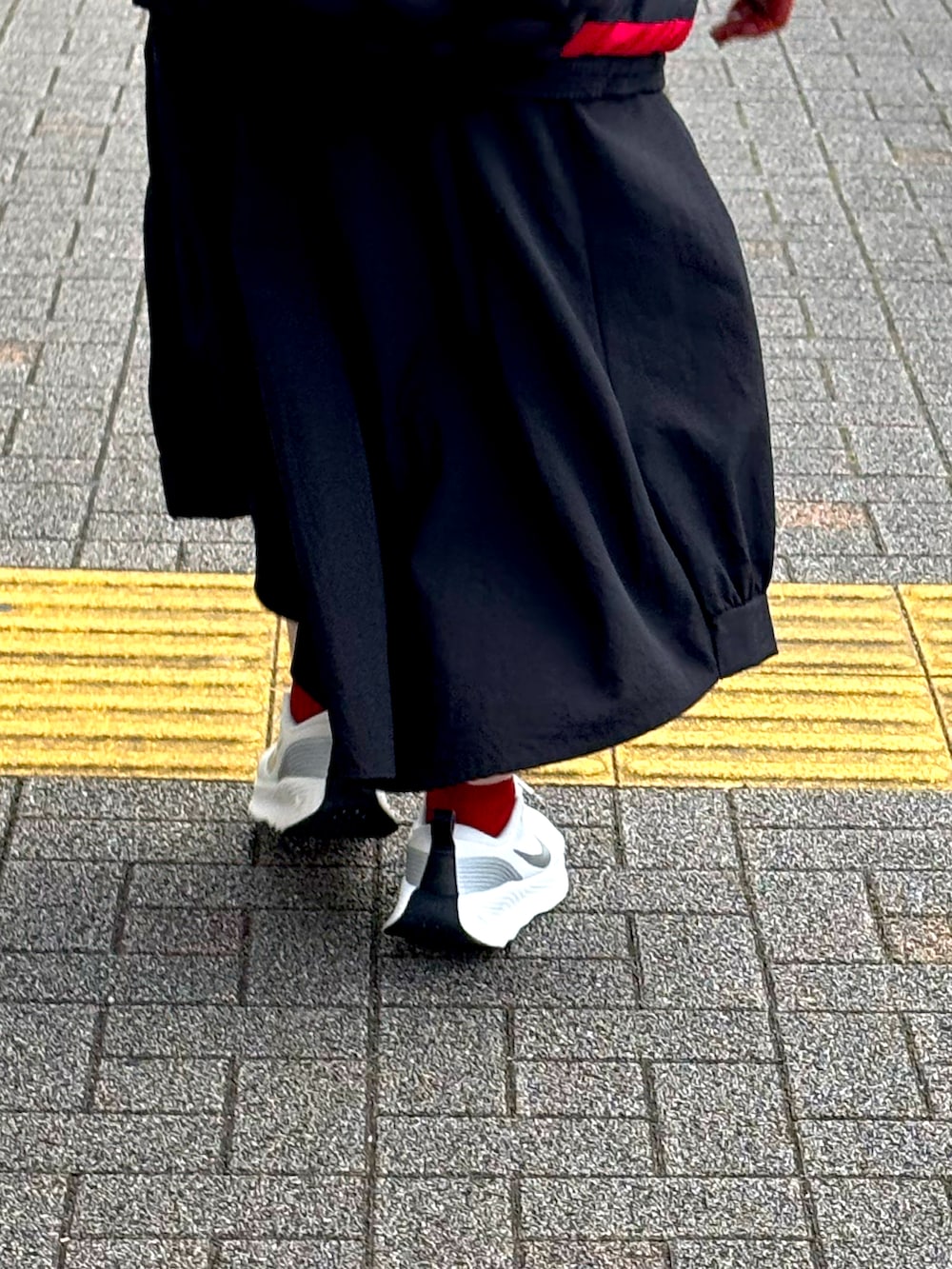 ブラック系のニット/セーター、ベージュ系のチェスターコート、ブルー系のデニムパンツを着用したメンズの冬コーディネートの5枚目の写真