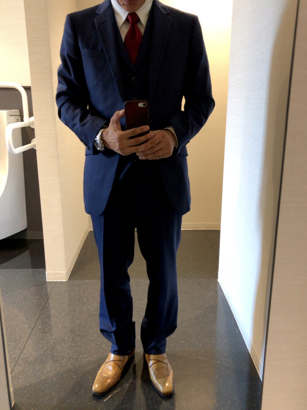 ベージュ系のローファー、ブラック系のビジネスバッグ、レッド系のネクタイを着用したメンズの春コーディネートの2枚目の写真