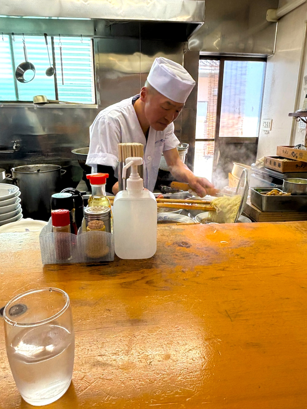 レッド系のシャツ/ブラウス、ブルー系のチェスターコート、グリーン系のチノパンツを着用したメンズの春コーディネートの5枚目の写真