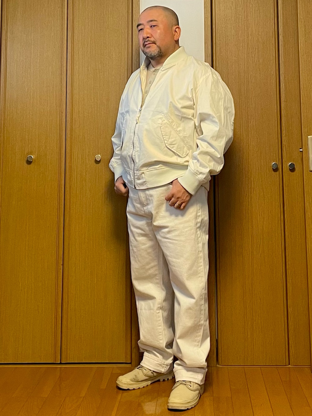 ホワイト系のデニムパンツ、ホワイト系のMA-1、ベージュ系のベストを着用したメンズの春コーディネートの2枚目の写真