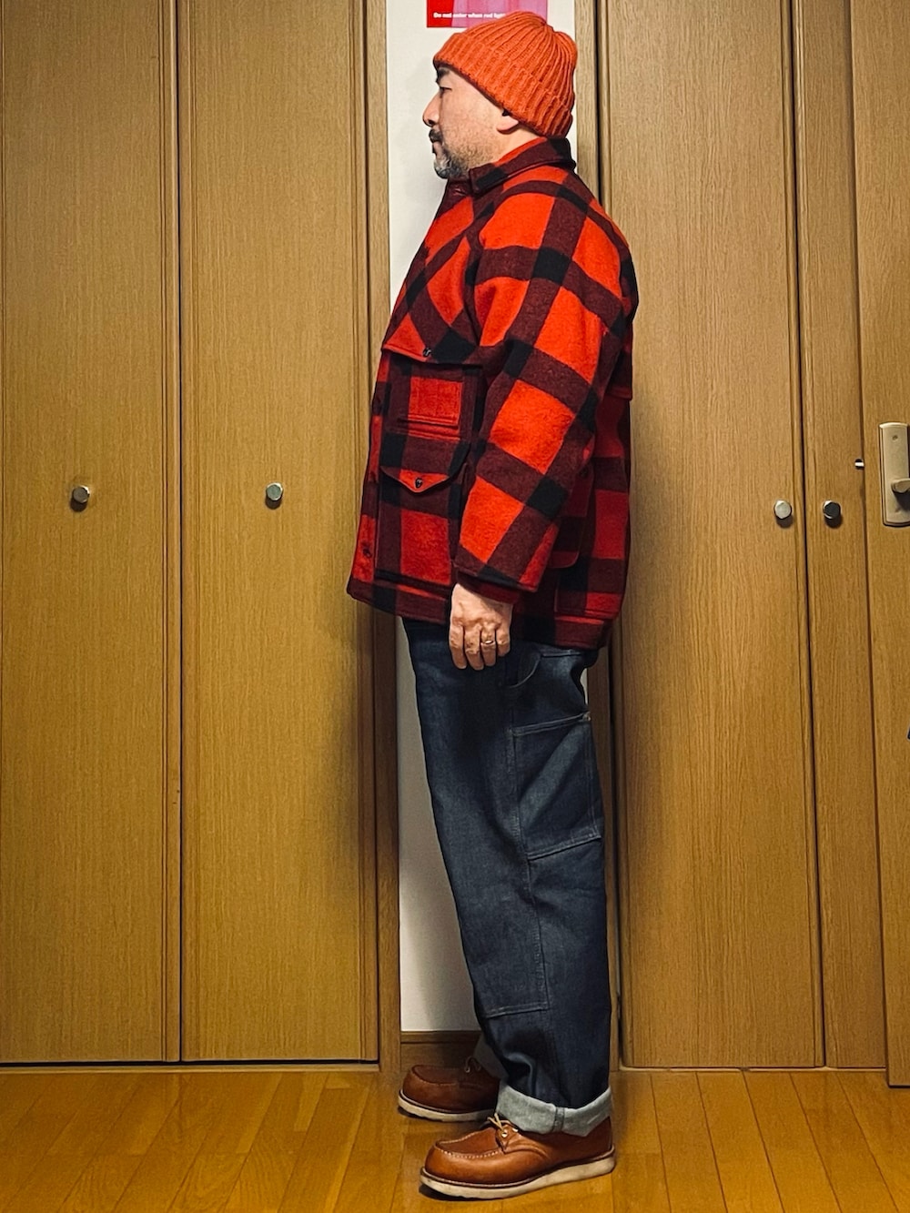 ブルー系のデニムパンツ、ブラウン系のブーツ、レッド系のベストを着用したメンズの春コーディネートの3枚目の写真