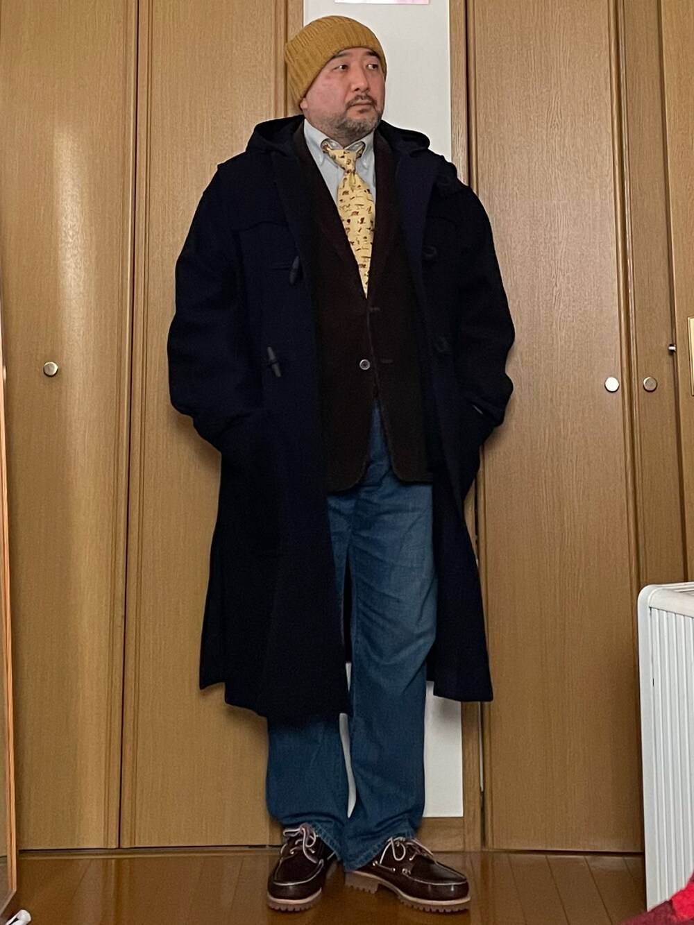 グリーン系のダッフルコート、イエロー系のネクタイ、ブラウン系のテーラードジャケットを着用したメンズの冬コーディネートの2枚目の写真