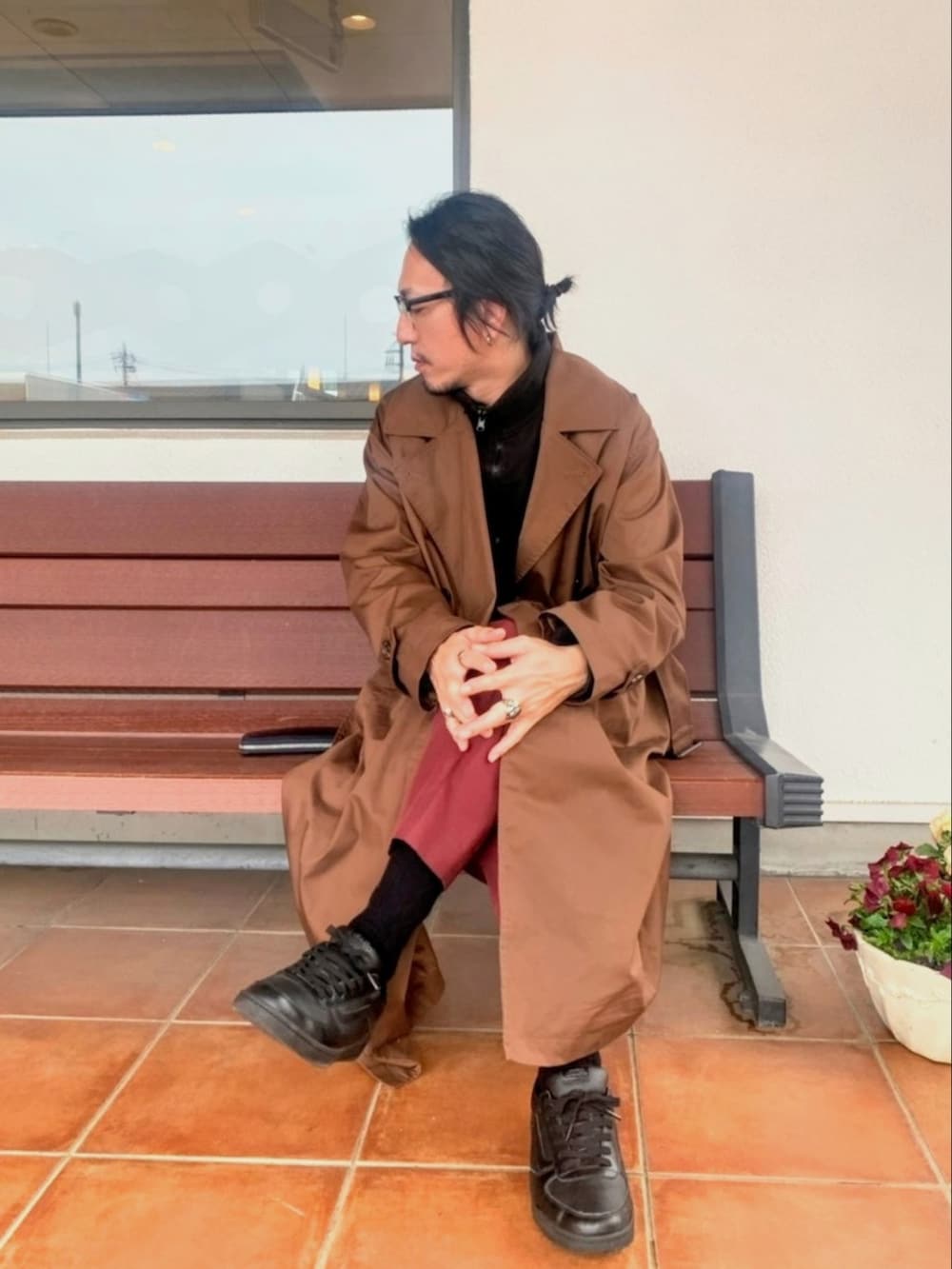 ブラウン系のトレンチコート、レッド系のスラックス、ブラック系のスニーカーを着用したメンズの春コーディネートの2枚目の写真