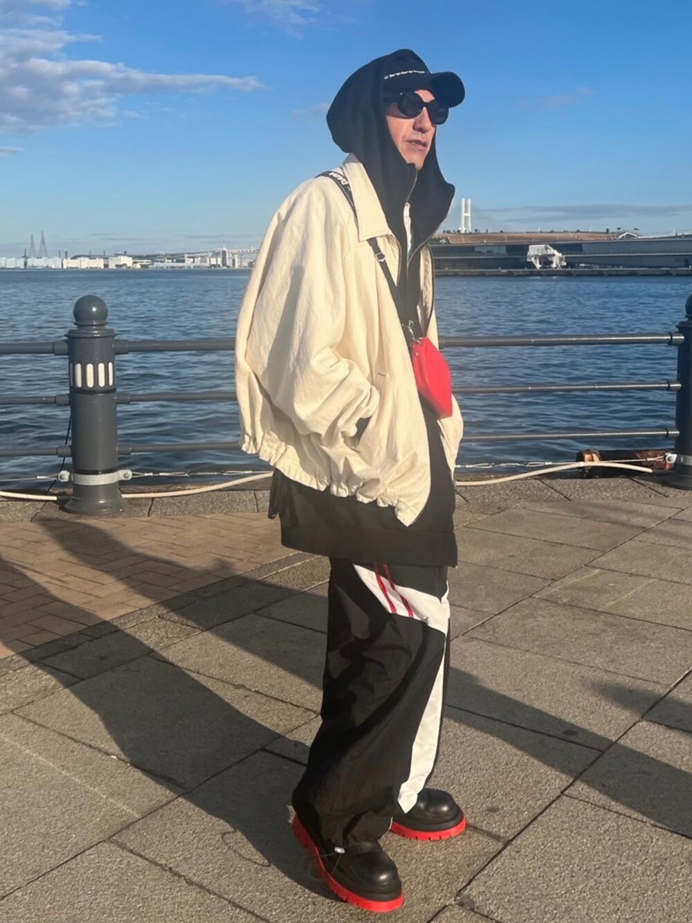 ブラック系のパーカー、ホワイト系のブルゾン、レッド系のショルダーバッグを着用したメンズの冬コーディネートの2枚目の写真