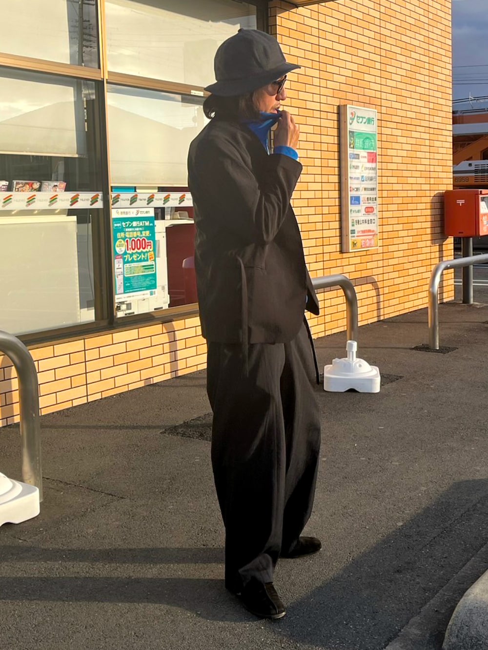 ブラック系のノーカラージャケット、ブラック系のスラックス、ブルー系のジャージを着用したメンズの春コーディネートの3枚目の写真