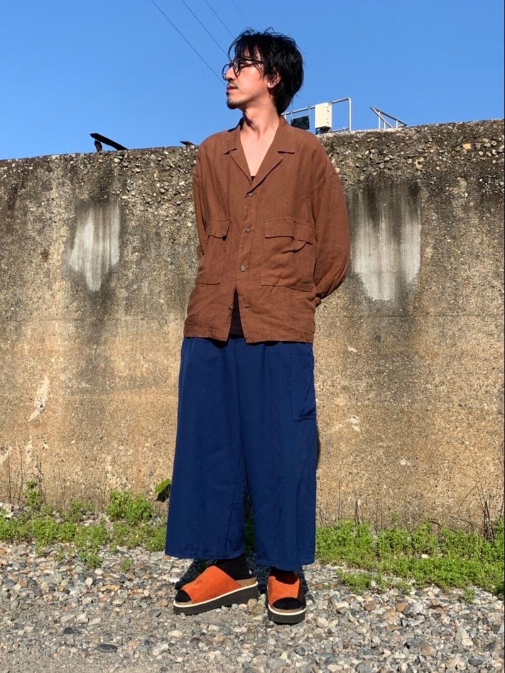 ブラウン系のシャツ/ブラウス、ブルー系のパンツ、オレンジ系のサンダルを着用したメンズの春コーディネートの2枚目の写真
