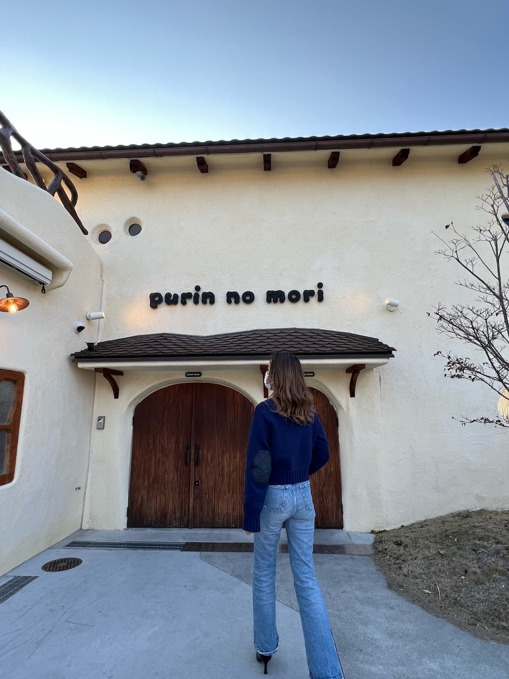 ブルー系のデニムパンツ、ブルー系のニット/セーター、ブラック系のブーツを着用したレディースの春コーディネートの2枚目の写真