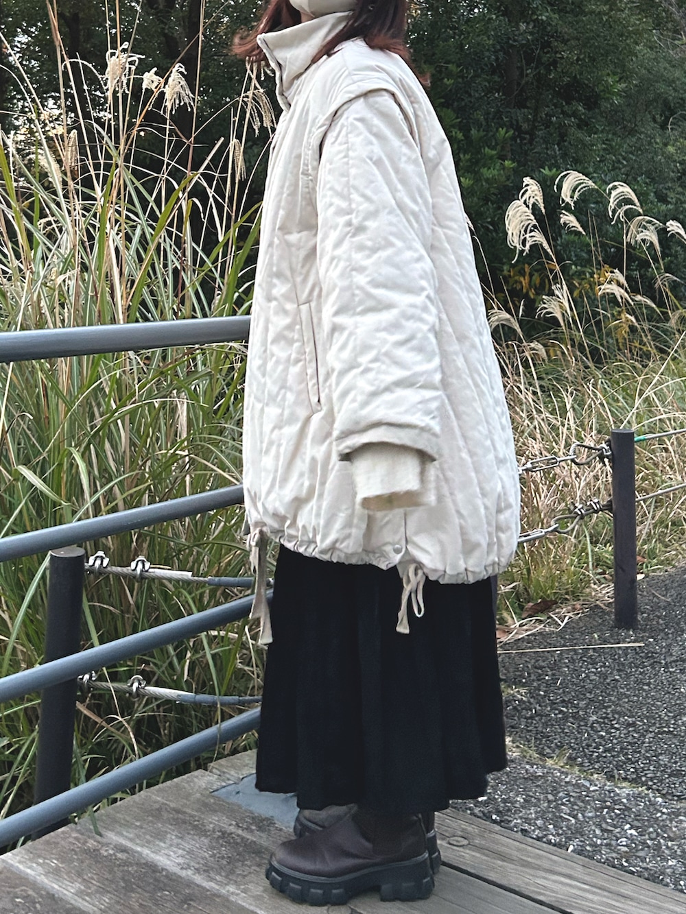 ブラック系のスカート、ホワイト系のダウンジャケット/コート、ブラウン系のブーツを着用したレディースの冬コーディネートの2枚目の写真