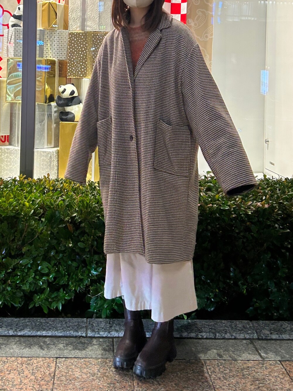 ブラウン系のチェスターコート、ブラウン系のニット/セーター、ブラウン系のブーツを着用したレディースの冬コーディネートの2枚目の写真