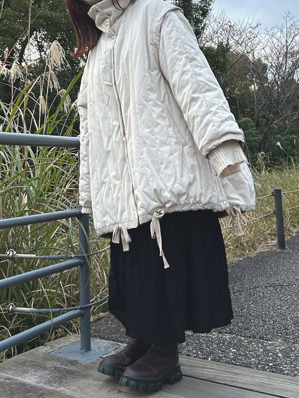 ブラック系のスカート、ホワイト系のダウンジャケット/コート、ブラウン系のブーツを着用したレディースの冬コーディネートの3枚目の写真