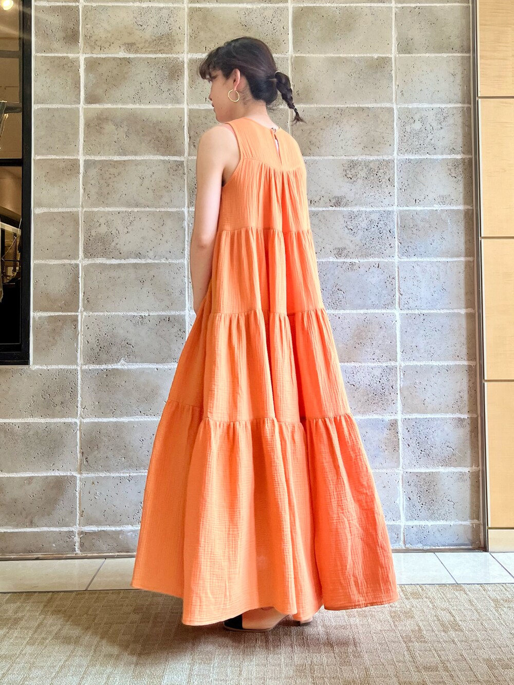 グリーン系のトートバッグ、オレンジ系のワンピース、ベージュ系のサンダルを着用したレディースの春コーディネートの2枚目の写真