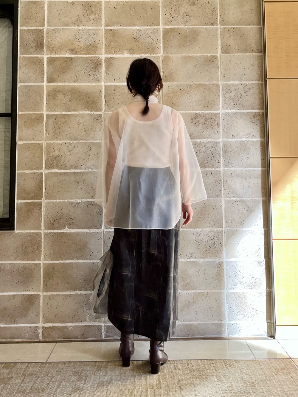 ブラック系のスカート、ブラウン系のブーツ、ホワイト系のタンクトップを着用したレディースの春コーディネートの2枚目の写真