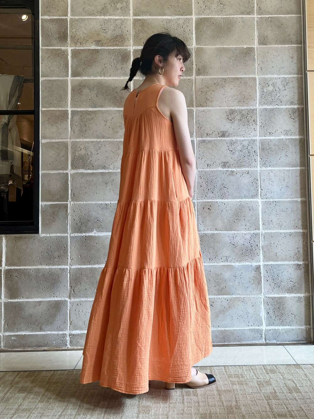 グリーン系のトートバッグ、オレンジ系のワンピース、ベージュ系のサンダルを着用したレディースの春コーディネートの3枚目の写真