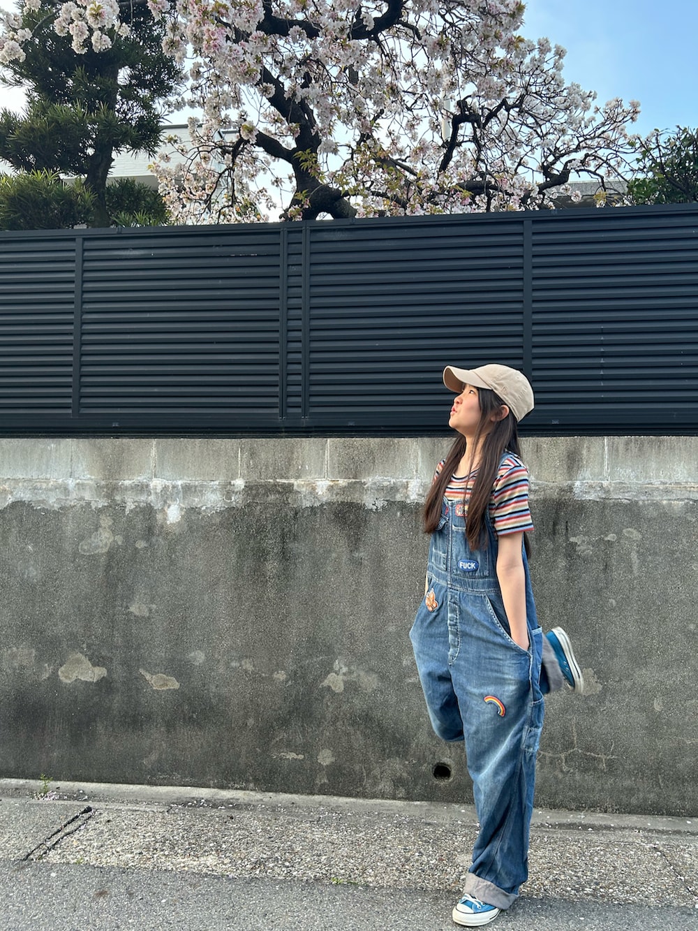 ブルー系のオールインワン・サロペット、グリーン系のスニーカー、ベージュ系のキャップを着用したキッズの春コーディネートの3枚目の写真