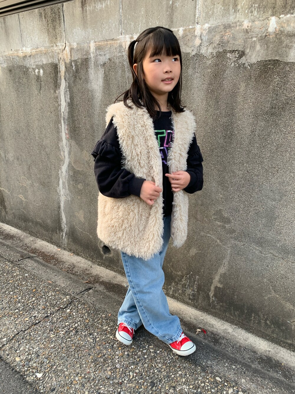 ブルー系のデニムパンツ、ベージュ系のベスト、ブラック系のスウェットを着用したキッズの冬コーディネートの2枚目の写真