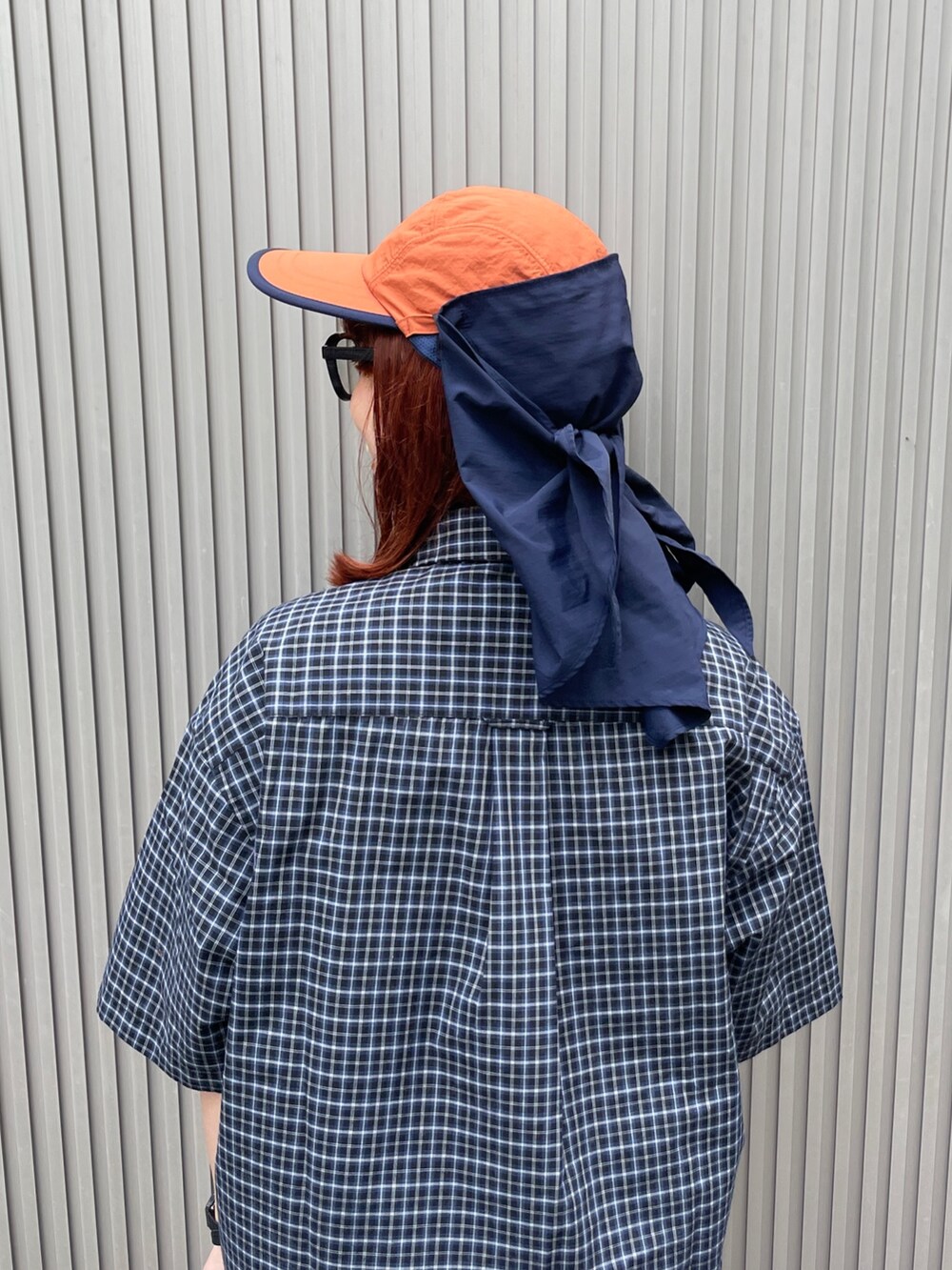 オレンジ系のキャップを着用したレディースの夏コーディネートの7枚目の写真