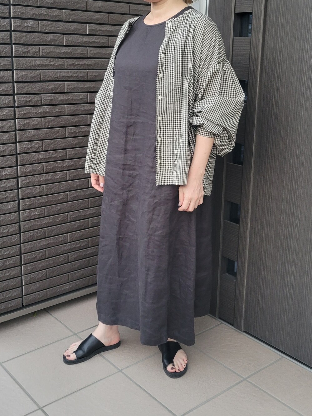 ブラック系のワンピース、ブラック系のシャツ/ブラウス、ブラック系のサンダルを着用したレディースの夏コーディネートの2枚目の写真